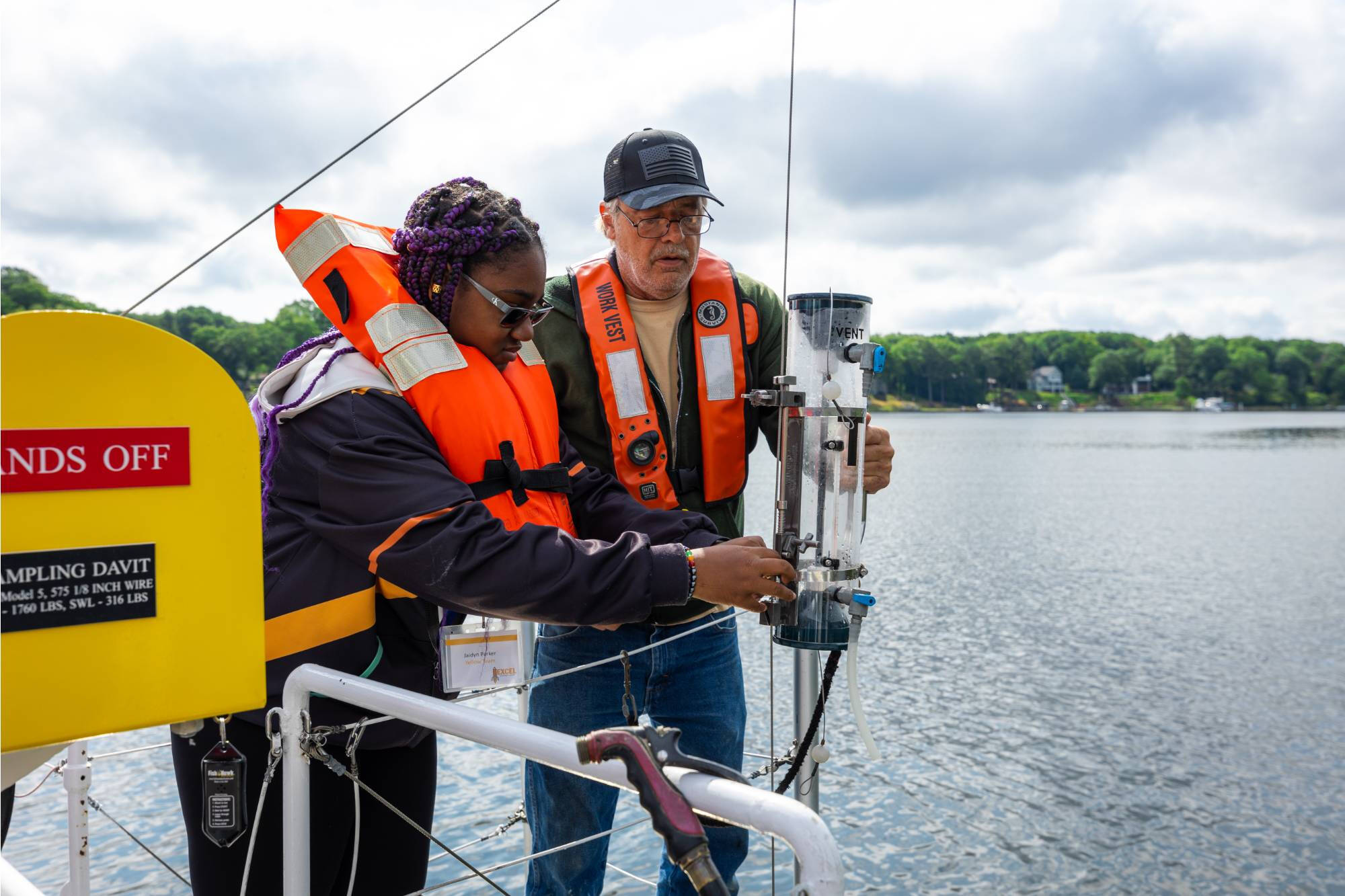An AWRI deckhand and visiting student collect water using a Van Dorn sampler onboard the D.J. Angus research vessel.